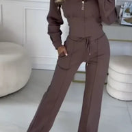 Person wearing a brown tracksuit in a room with light-colored walls and flooring.