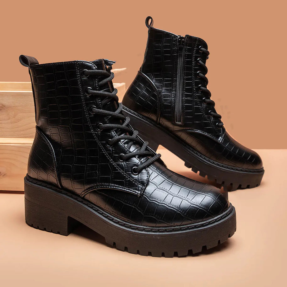 Black crocodile-patterned boots on a beige background