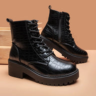 Black crocodile-patterned boots on a beige background