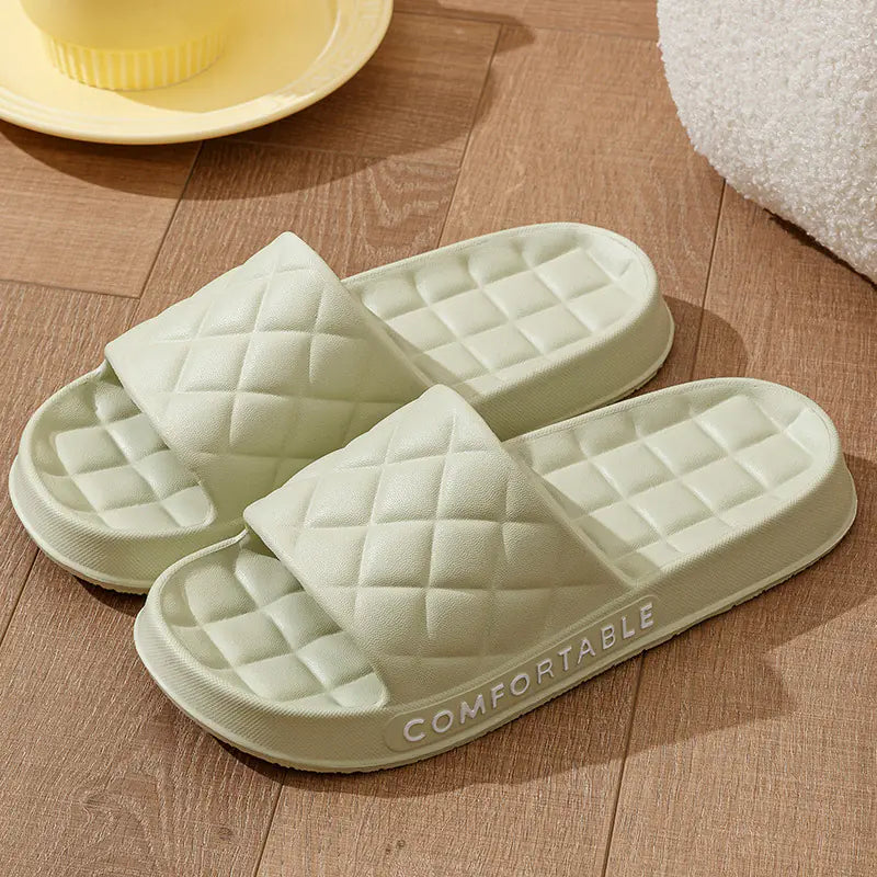 Light green quilted slippers on a wooden floor with 'COMFORTABLE' text.