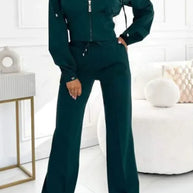 Woman wearing a green tracksuit in a minimalistic room.