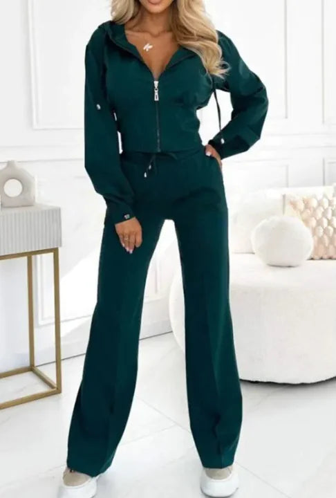 Woman wearing a green tracksuit in a minimalistic room.