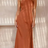 Woman wearing a rust-colored dress against a neutral background