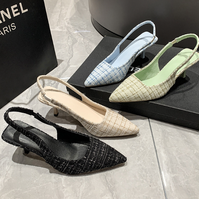 Four pairs of women's slingback shoes in different colors on a marble surface with a Chanel logo in the background.