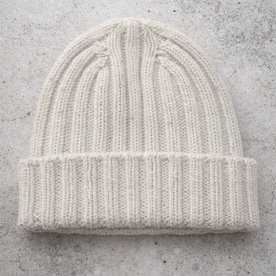 White knit beanie on a gray concrete surface