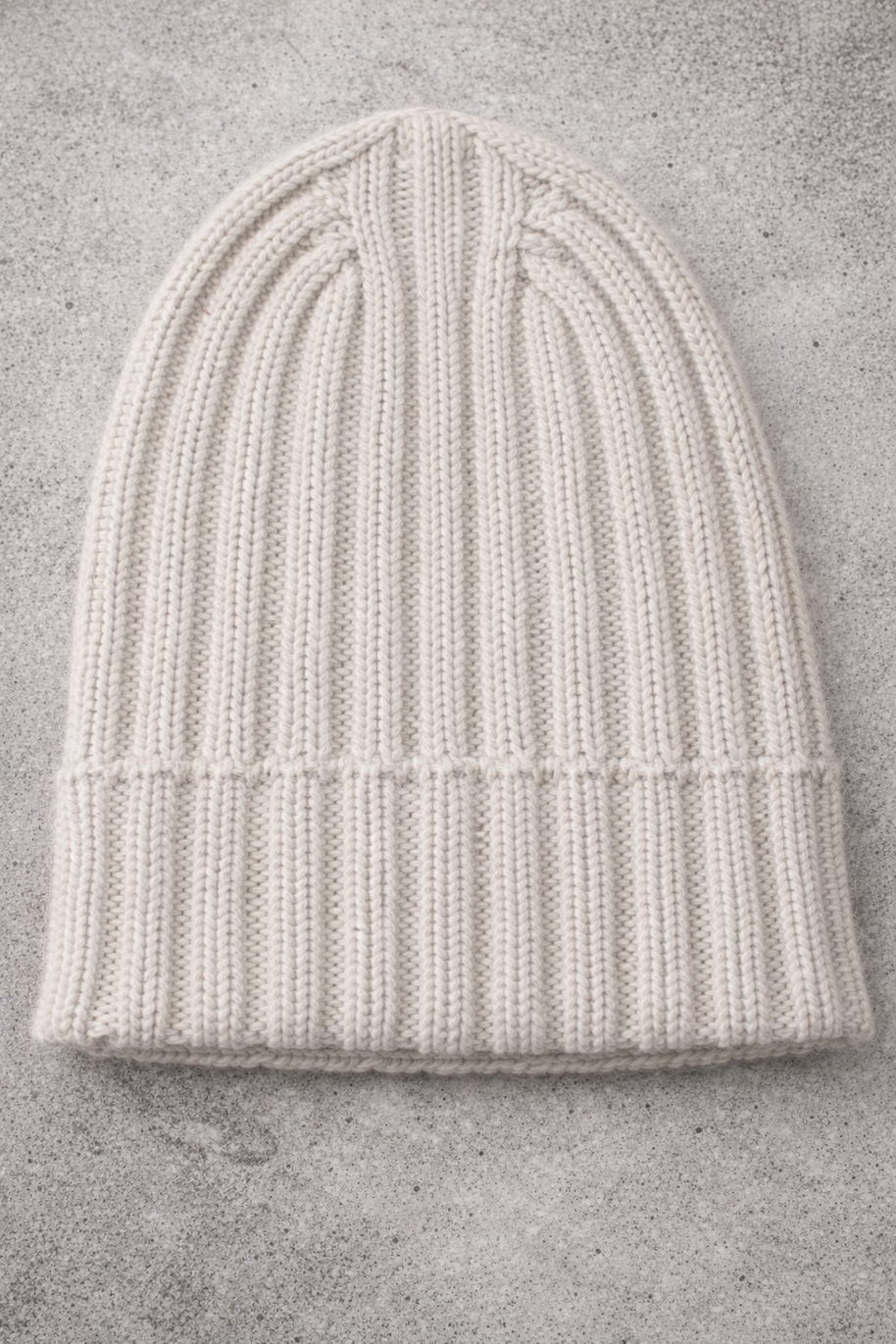 White knit beanie on a gray concrete surface