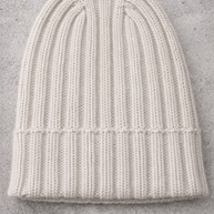 White knit beanie on a gray concrete surface