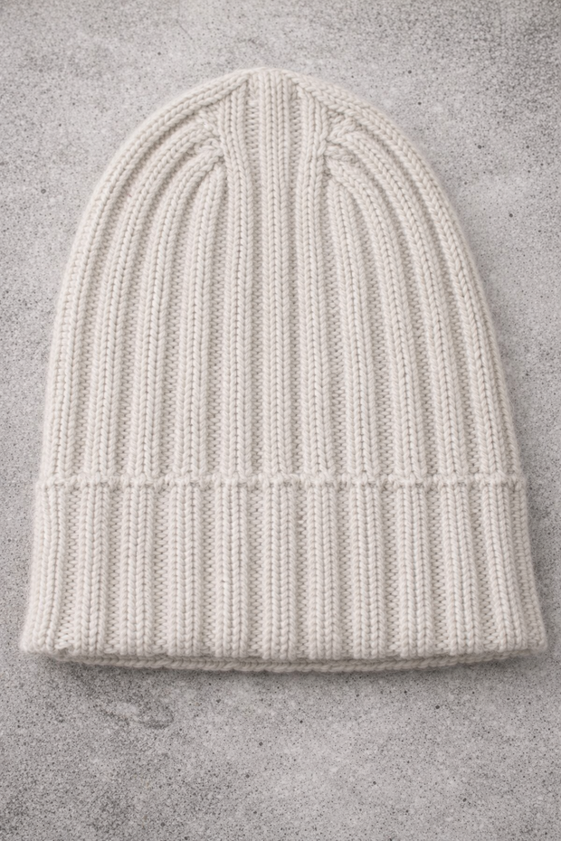 White knit beanie on a gray concrete surface