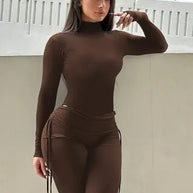 Woman wearing a brown outfit posing indoors.