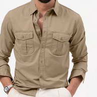 Man wearing a beige button-up shirt with rolled-up sleeves on a white background