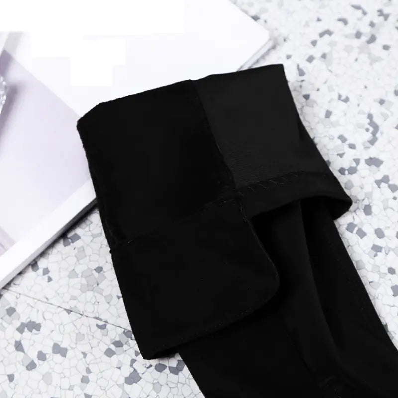 Folded black fabric on a textured white surface