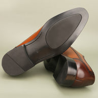 Close-up of brown leather shoes with dark soles on a light background